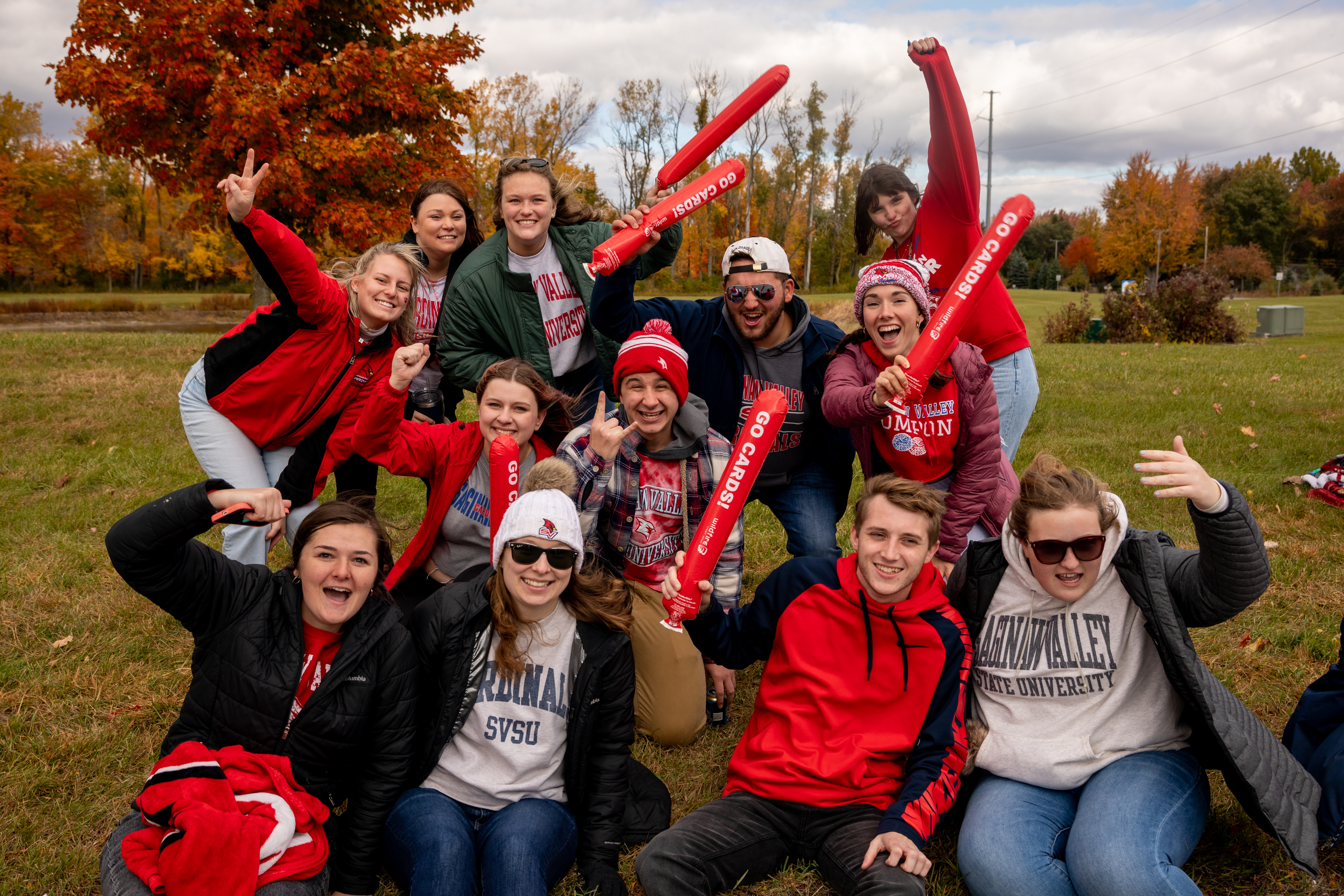Group of 12 students in SVSU gear cheering at the SVSU Homecoming football game.